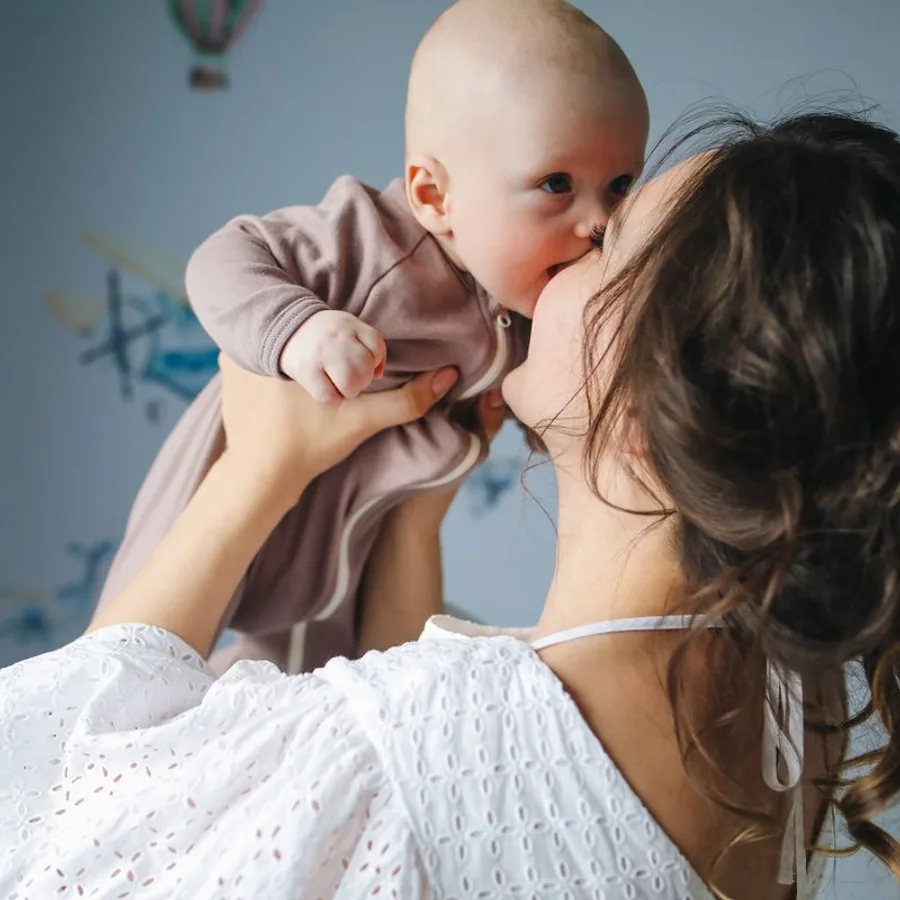 Una mamá besando a su bebé en brazos